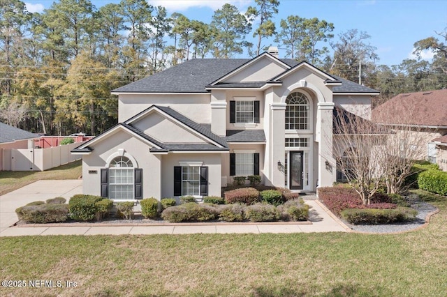 view of front of home with a front yard, fence, and stucco siding