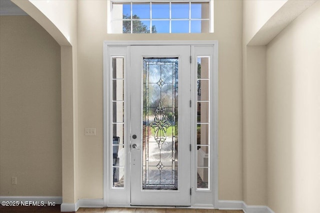 foyer entrance with arched walkways and baseboards