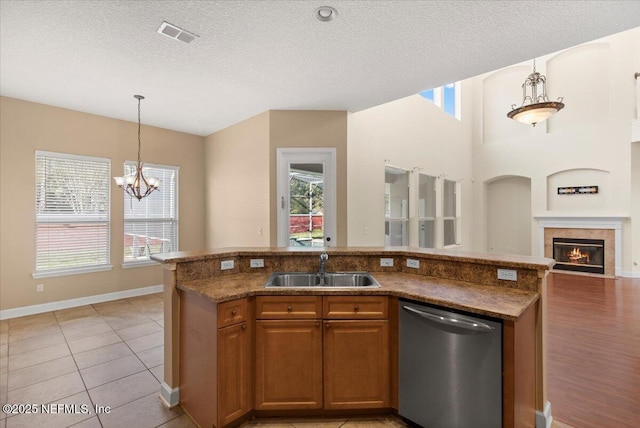 kitchen with dishwasher, a glass covered fireplace, plenty of natural light, and a sink