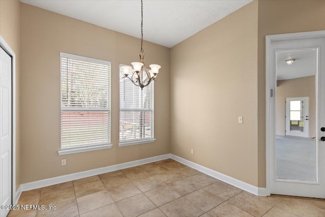 unfurnished dining area with an inviting chandelier, light tile patterned floors, and baseboards