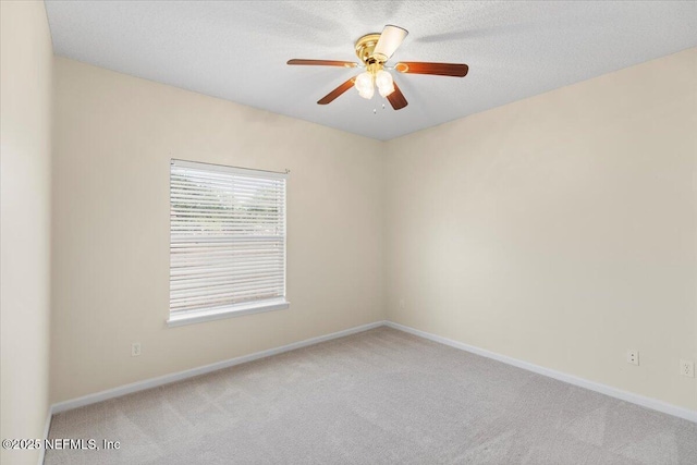 spare room with carpet floors, baseboards, and a ceiling fan