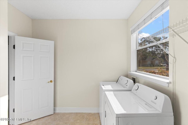 laundry area with laundry area, light tile patterned flooring, washing machine and clothes dryer, and baseboards