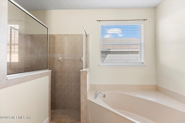 bathroom featuring a textured ceiling, walk in shower, and a bath