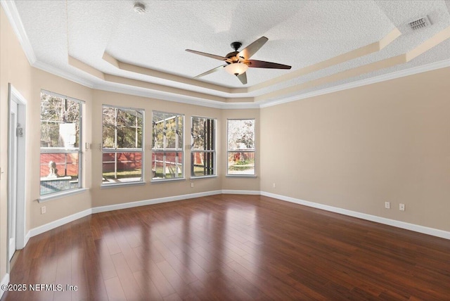 spare room with a textured ceiling, a raised ceiling, and wood finished floors