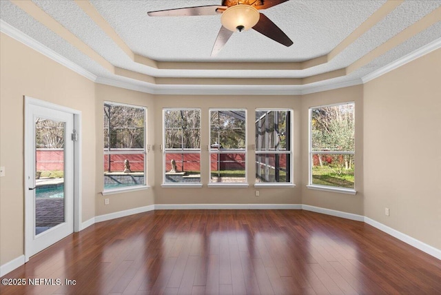 unfurnished sunroom featuring a tray ceiling, plenty of natural light, and ceiling fan