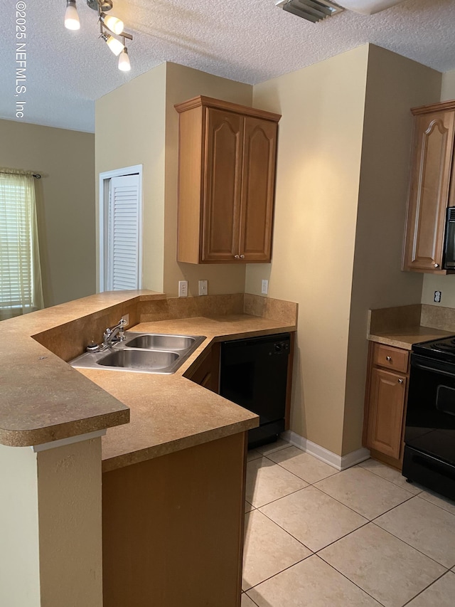 kitchen with light tile patterned floors, a peninsula, a textured ceiling, black appliances, and a sink