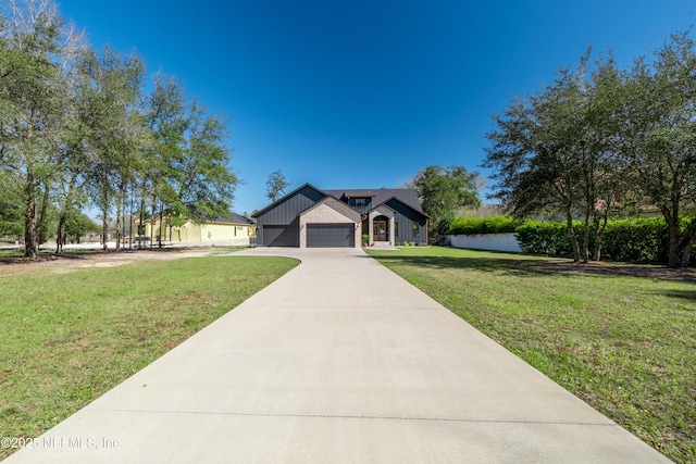 view of front of home with board and batten siding, a front yard, a water view, and driveway