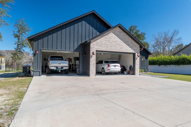 garage featuring central air condition unit, driveway, and fence