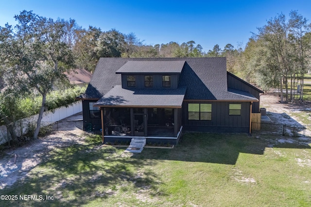 back of house featuring a shingled roof, fence, a sunroom, a yard, and board and batten siding