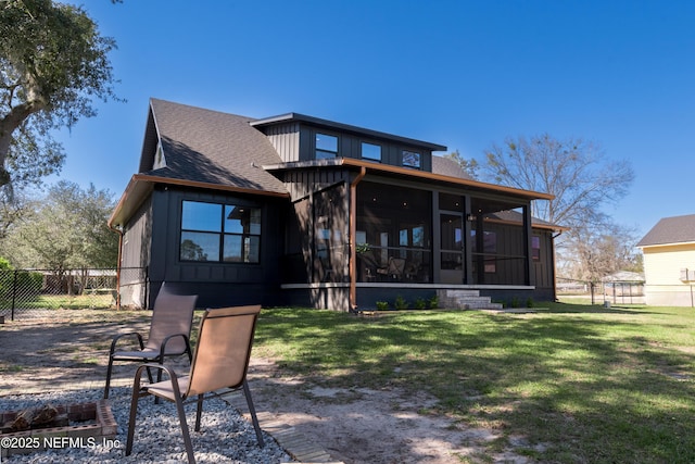 back of house featuring a yard, a sunroom, fence, and a shingled roof