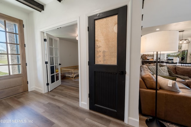 doorway to outside with beamed ceiling, wood finished floors, and baseboards