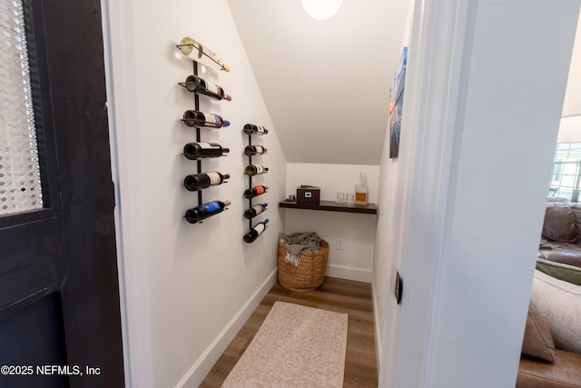 interior space with lofted ceiling, baseboards, and wood finished floors