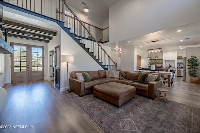 living room with stairs, a high ceiling, wood finished floors, and recessed lighting