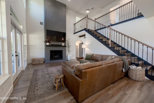 living room featuring visible vents, a towering ceiling, wood finished floors, stairs, and a fireplace