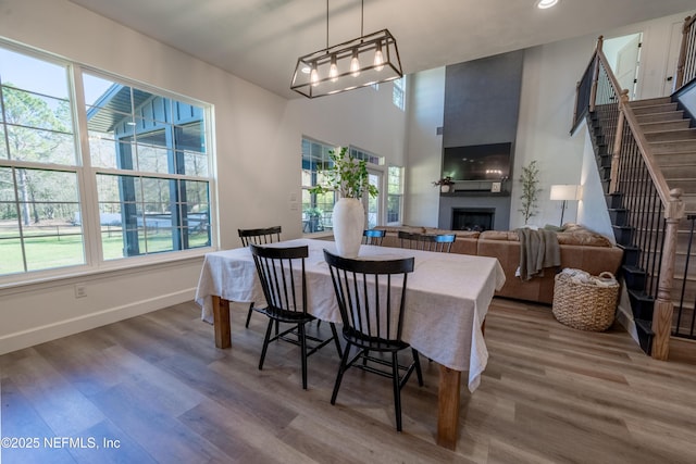 dining room with stairs, a wealth of natural light, a fireplace, and wood finished floors