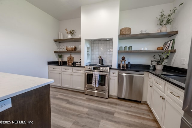 kitchen with light wood-style flooring, appliances with stainless steel finishes, open shelves, and decorative backsplash