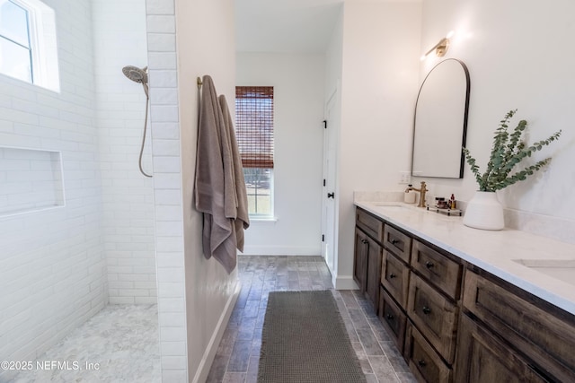 bathroom with double vanity, plenty of natural light, and a tile shower