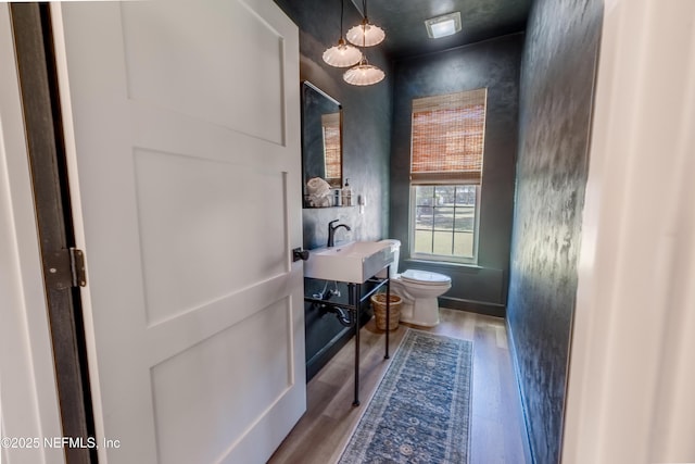 half bathroom with vanity, toilet, and wood finished floors