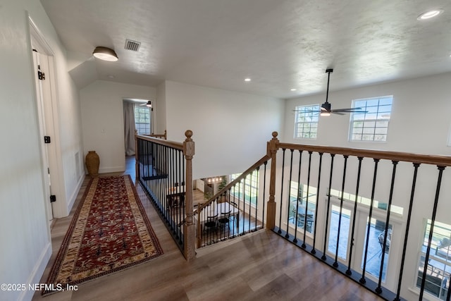 hall with recessed lighting, wood finished floors, visible vents, an upstairs landing, and baseboards