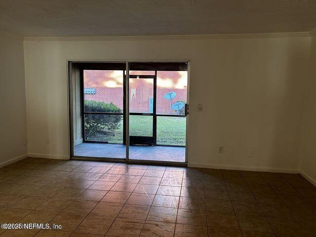 unfurnished room featuring baseboards, ornamental molding, and tile patterned flooring