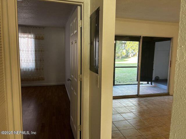 hall featuring baseboards, ornamental molding, and a textured ceiling