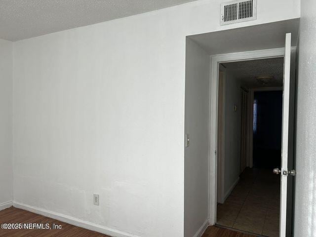 unfurnished room featuring dark wood-style floors, baseboards, and visible vents