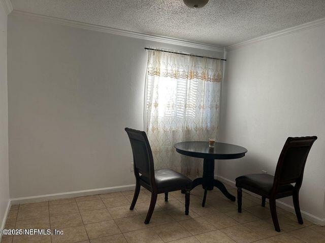 dining space featuring light tile patterned floors, a textured ceiling, baseboards, and crown molding