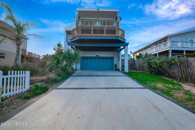 view of front of property featuring stucco siding, concrete driveway, fence, a balcony, and a garage