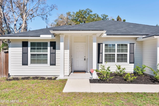 view of front of property featuring roof with shingles, fence, and a front yard