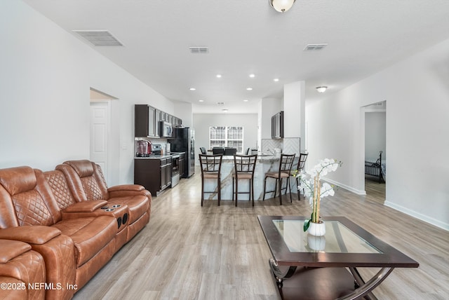 living area featuring light wood-style flooring, recessed lighting, visible vents, and baseboards