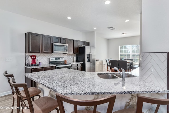 kitchen with tasteful backsplash, appliances with stainless steel finishes, a kitchen breakfast bar, a peninsula, and a sink