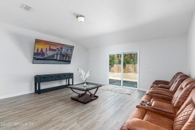 living area featuring lofted ceiling, baseboards, visible vents, and wood finished floors