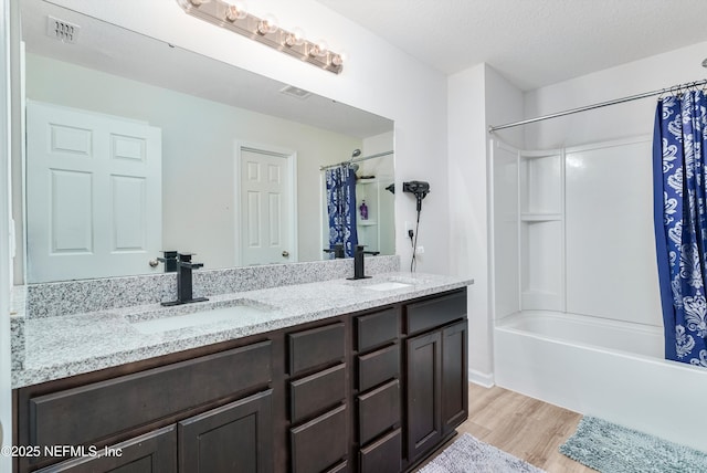 full bath with double vanity, visible vents, a sink, and wood finished floors