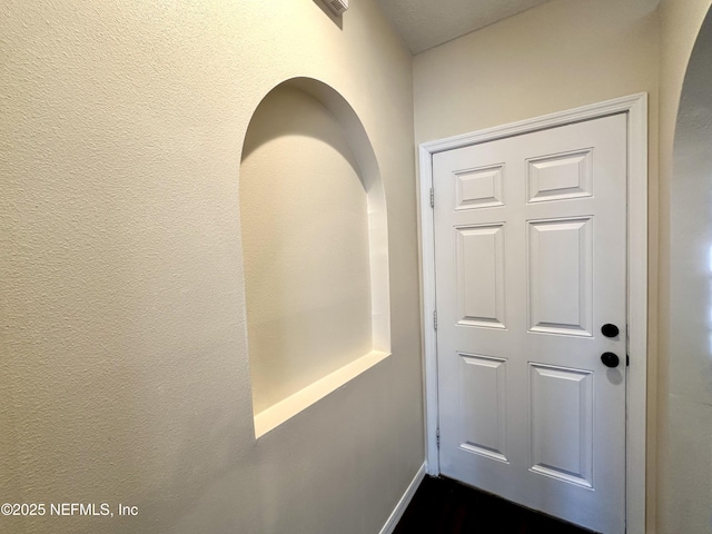 doorway with arched walkways and a textured wall