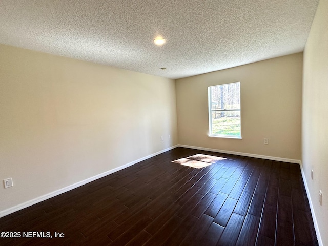 unfurnished room featuring baseboards, dark wood finished floors, and a textured ceiling