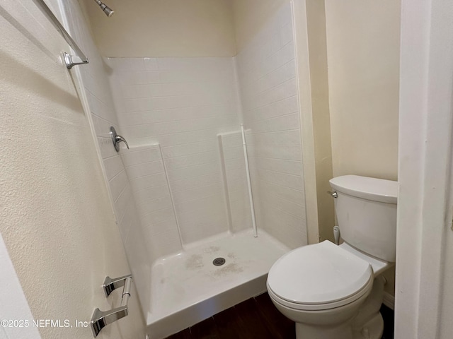 full bathroom with toilet, a shower stall, and wood finished floors