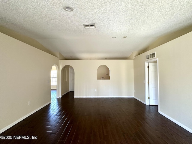 spare room with dark wood-style floors, arched walkways, and visible vents