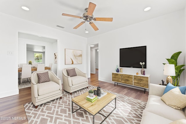 living area with baseboards, wood finished floors, visible vents, and recessed lighting