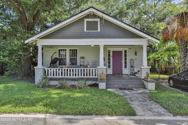 bungalow-style home with covered porch, fence, and a front lawn