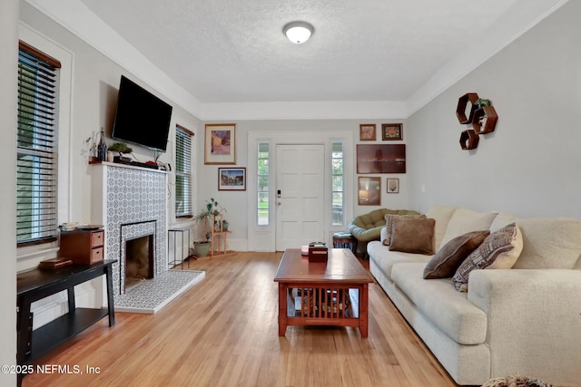 living room with a tile fireplace, light wood-style flooring, and a textured ceiling