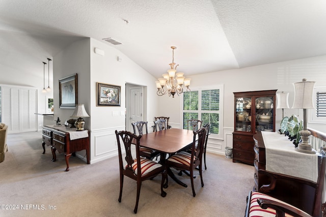 dining area featuring lofted ceiling, light colored carpet, visible vents, wainscoting, and an inviting chandelier