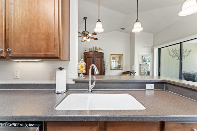 kitchen featuring dark countertops, visible vents, a sink, and lofted ceiling