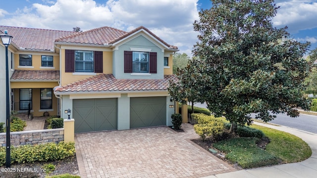 view of front facade with a garage, stucco siding, decorative driveway, and a tiled roof