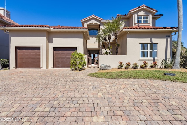 mediterranean / spanish-style house featuring a tile roof, a chimney, an attached garage, decorative driveway, and stucco siding