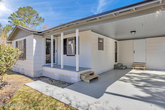 property entrance with crawl space, a carport, a porch, and driveway