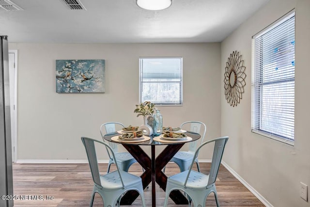 dining space with light wood finished floors, visible vents, and a wealth of natural light