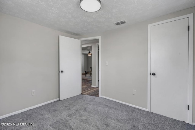 unfurnished bedroom with baseboards, visible vents, carpet floors, and a textured ceiling