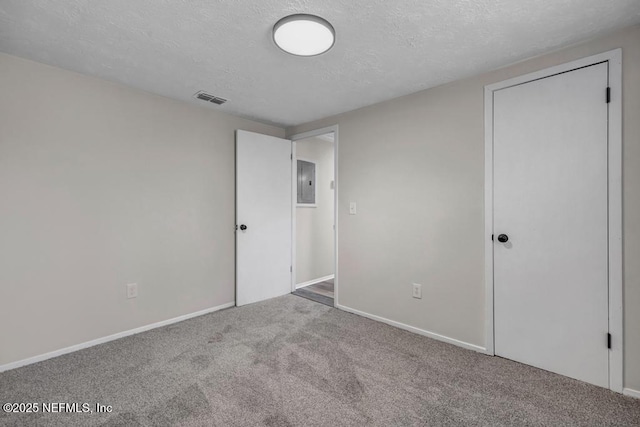 unfurnished bedroom with carpet, baseboards, visible vents, electric panel, and a textured ceiling