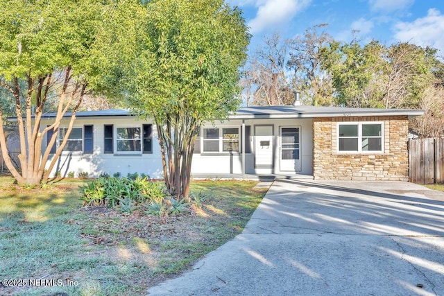 ranch-style home with stone siding, fence, and driveway