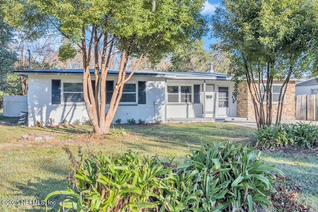 ranch-style home featuring fence, a front lawn, and stucco siding